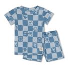 Baby zit op de bank met een verwonderde blik in blauwe shortama